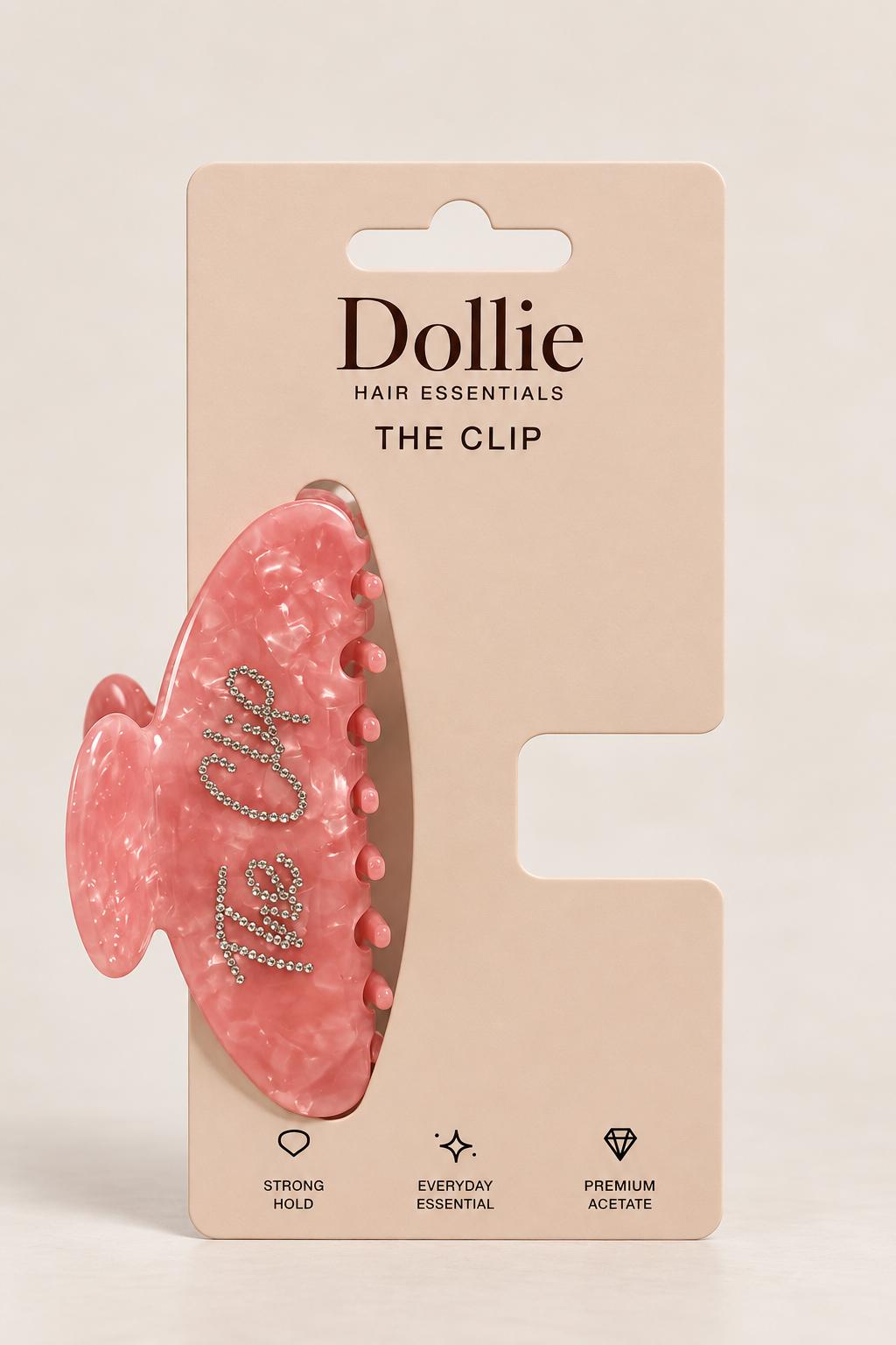 The Clip roz perlat pe ambalajul Dollie Hair Essentials